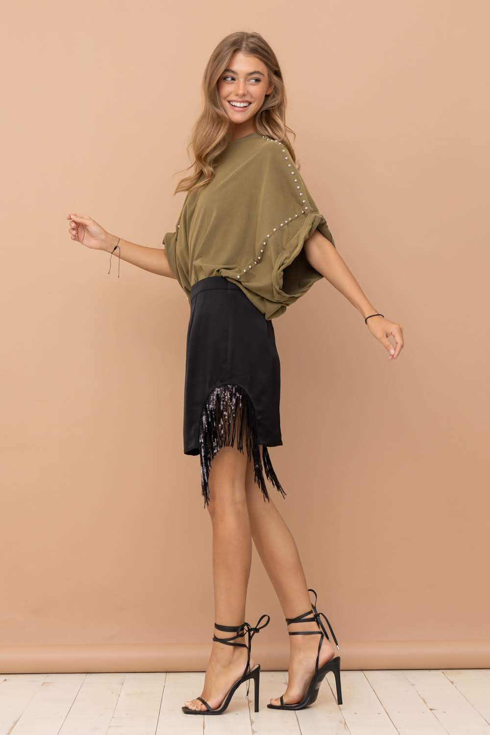 Add a touch of urban western chic to your wardrobe with the Dana Side Cut Out Sequin Fringe Mini Skirt. Featuring a side-cut out design and shimmering sequin fringe, this black mini skirt from Blue B is perfect for adding a boho-chic and cowgirl flair to your style. Elevate your western fashion game with this stylish piece.