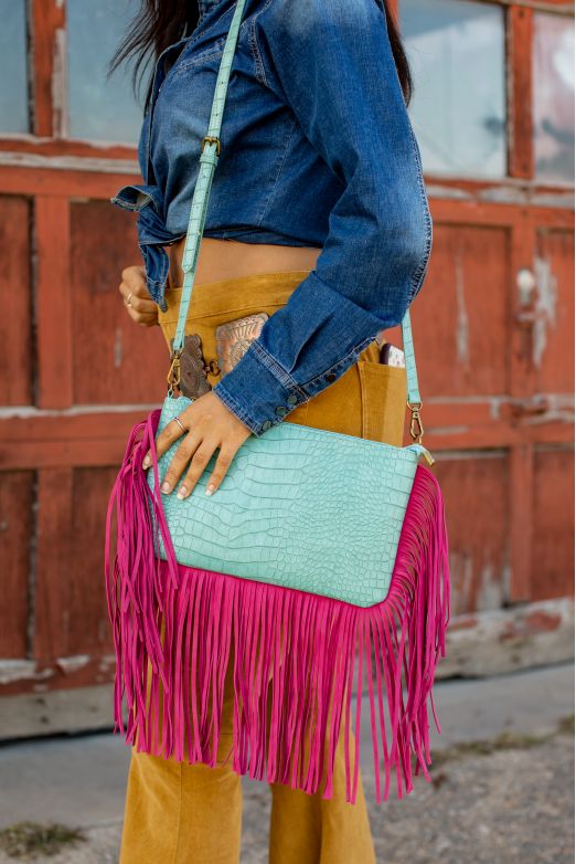 Elevate your style with the Nina Teal and Pink Shoulder Bag! The perfect combination of gipsy, boho, and chic styles, this bag is a must-have for any fashion-forward woman. With its teal and pink fringe design, it adds a touch of western flair to any outfit. Carry all your essentials in style with this urban western accessory.