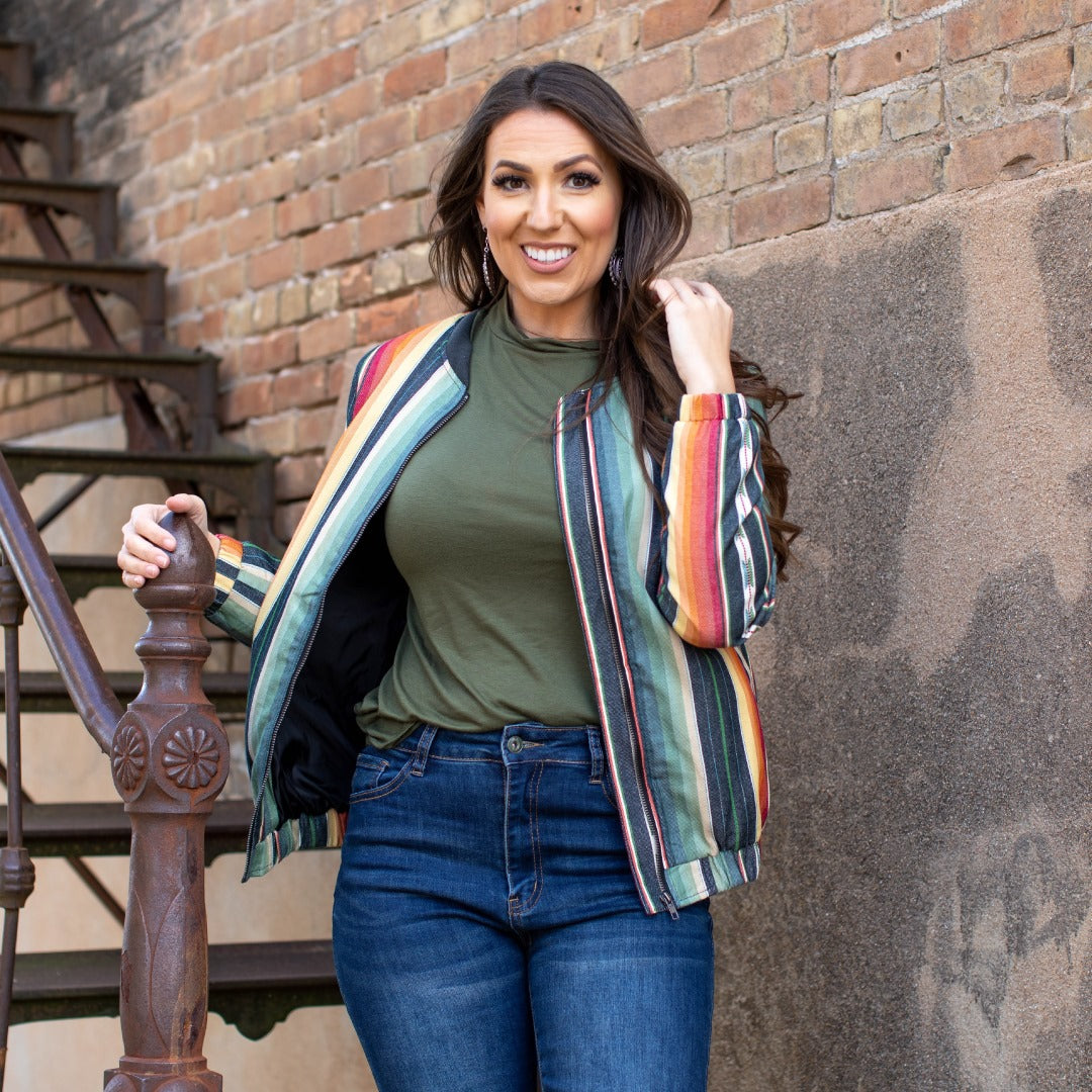Elevate your style with our Serape Bomber Jacket! This bohemian-chic piece seamlessly blends Western fashion with urban flair. With its eye-catching serape print and versatile denim material, it's a must-have for any boho-cowgirl wardrobe. Stand out from the crowd and express your unique sense of style with our one-of-a-kind jacket.