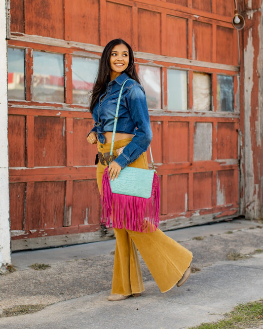 Elevate your style with the Nina Teal and Pink Shoulder Bag! The perfect combination of gipsy, boho, and chic styles, this bag is a must-have for any fashion-forward woman. With its teal and pink fringe design, it adds a touch of western flair to any outfit. Carry all your essentials in style with this urban western accessory.