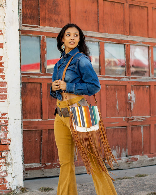 Elevate your style with the Jane Serape Shoulder Bag. This Western and Boho inspired bag boasts a unique combination of serape and cowhide, complete with stylish fringes. Perfect for the fashion-forward woman, this bag effortlessly blends together Gipsy, Chic, and Cowgirl styles. With a convenient crossbody design, it's the perfect accessory for any Bohemian or Urban Western look. Embrace a new level of fashion with this must-have women's bag.